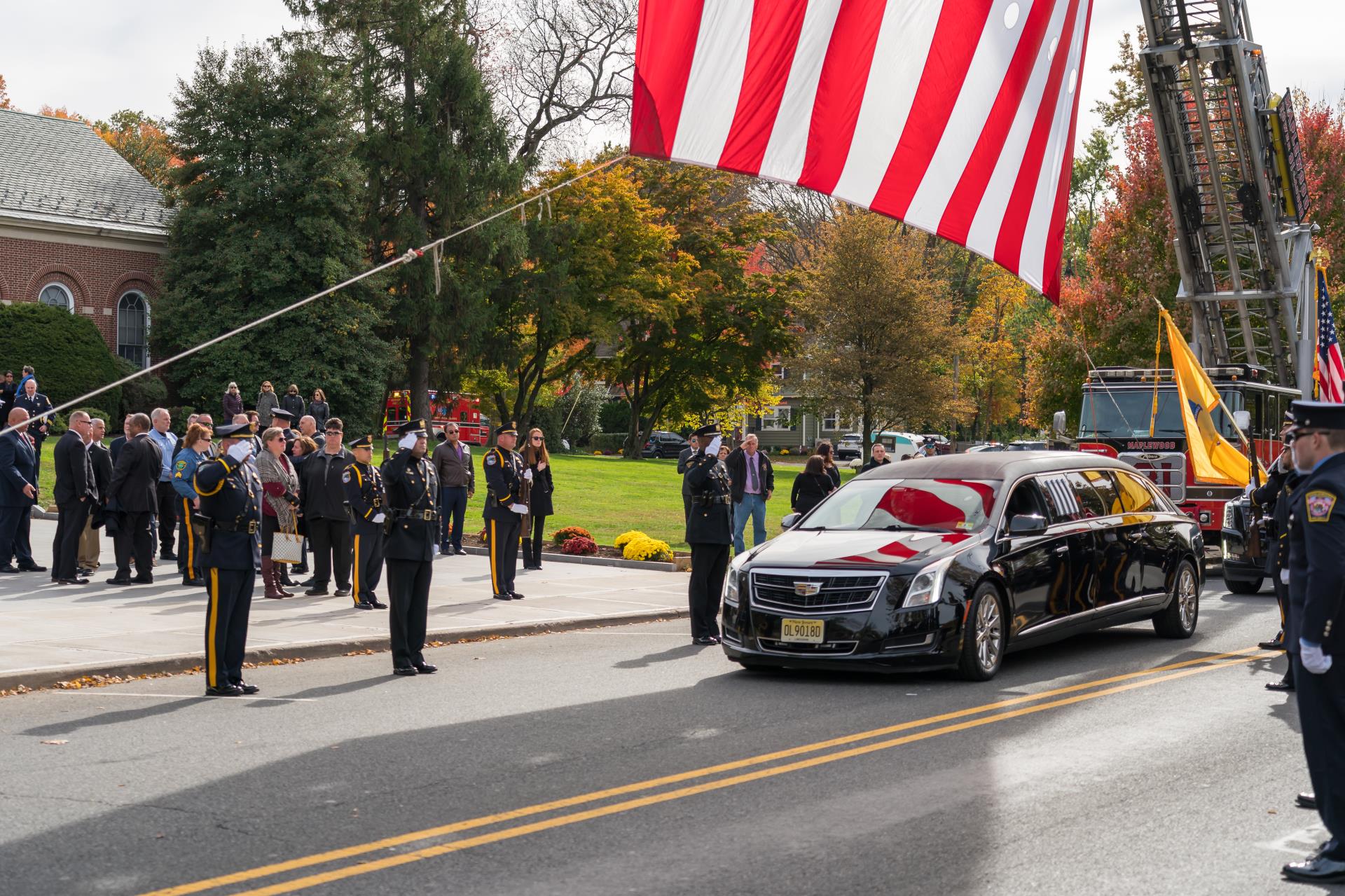 Image of Officers saluting Chief DeVaul's hearse as it departs from Town Hall following his funeral ceremony.